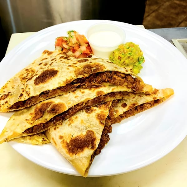 Fuego Mexican Kitchen's quesadillas with salsa, sour cream, and guacamole on a white plate.