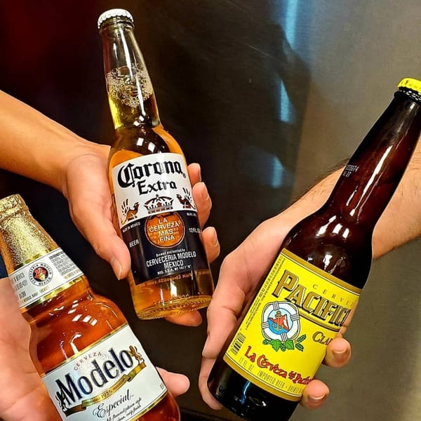 Three hands holding bottles of Corona Extra, Modelo Especial, and Pacifico Clara Mexican beers.