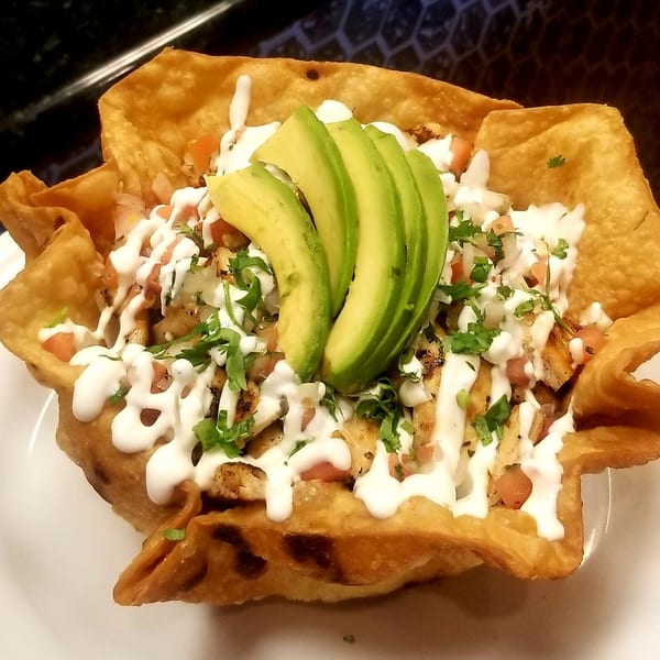Fuego Mexican Kitchen's taco salad in a crispy tortilla bowl, topped with chicken, avocado, and sour cream.